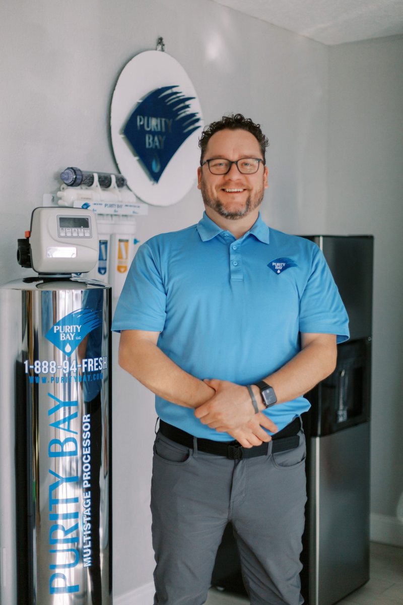 Tyler Greninger of Purity Bay standing beside water-treatment equipment